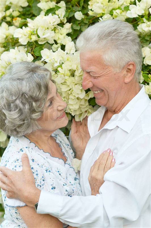 Happy elder couple on white flowers background, stock photo