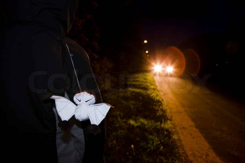 A person wearing a jacket with reflector while walking in the dark, stock photo