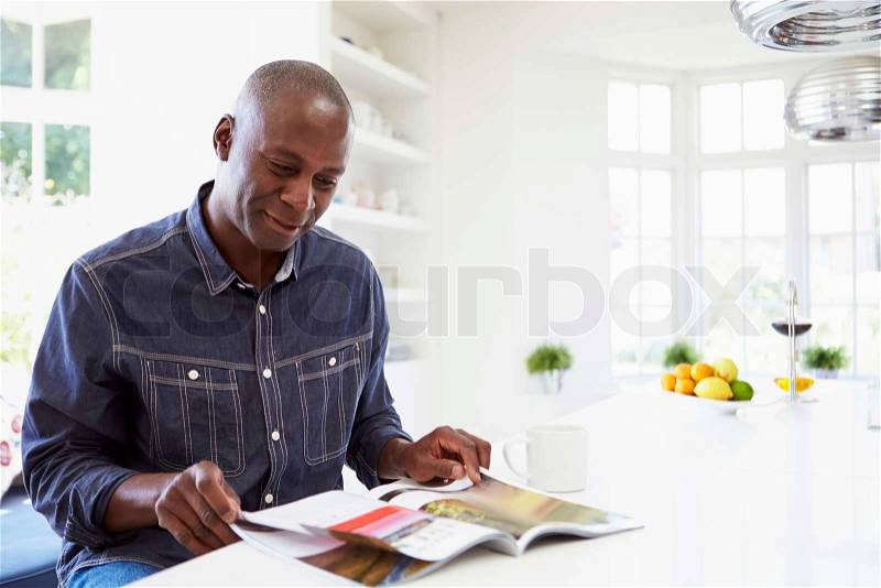 African American Man Reading Magazine At Home, stock photo
