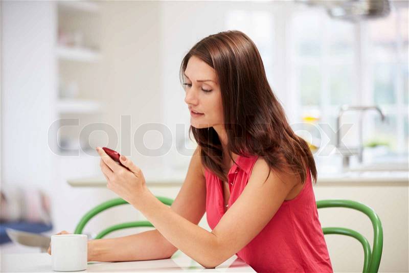 Hispanic Woman Sending Text Message At Home, stock photo