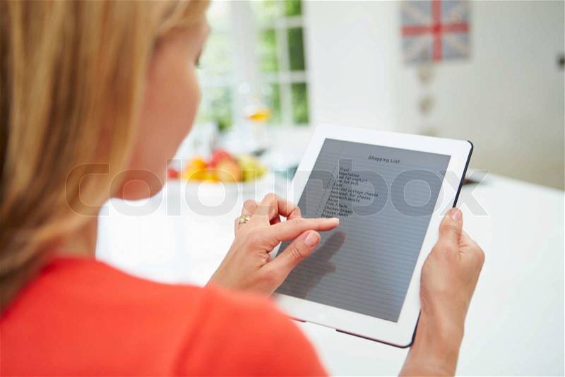 Woman Using Digital Tablet To Write Shopping List At Home, stock photo
