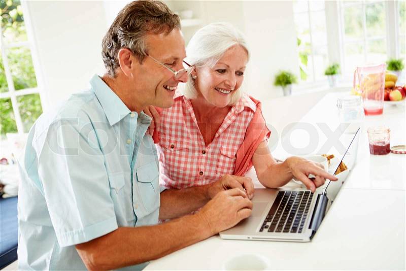 Middle Aged Couple Looking At Laptop Over Breakfast, stock photo