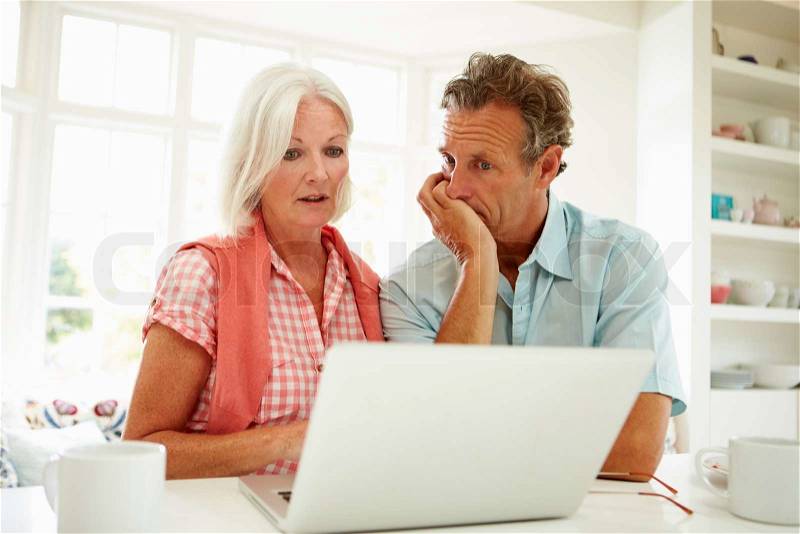 Worried Middle Aged Couple Looking At Laptop, stock photo