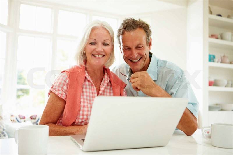 Smiling Middle Aged Couple Looking At Laptop, stock photo