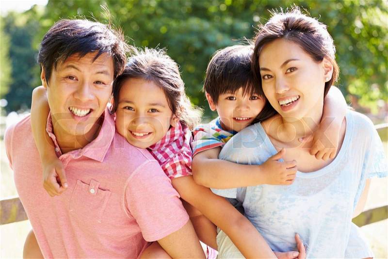 Portrait Of Asian Family Enjoying Walk In Summer Countryside, stock photo