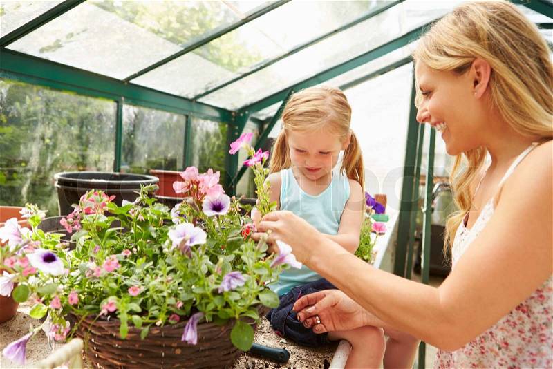 Mother And Daughter Growing Plants In Greenhouse, stock photo