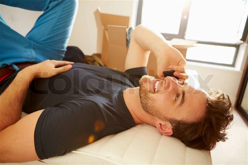 Man Moving Into New Home Talking On Mobile Phone, stock photo