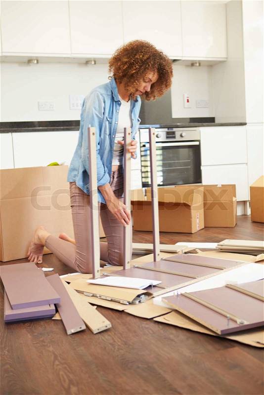 Woman Putting Together Self Assembly Furniture In New Home, stock photo