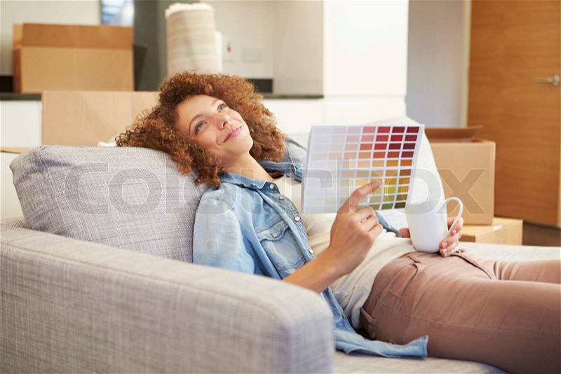 Woman Sitting On Sofa Looking At Paint Charts, stock photo