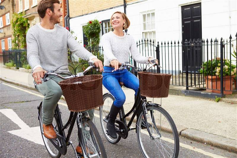 Couple Cycling Along Urban Street Together, stock photo