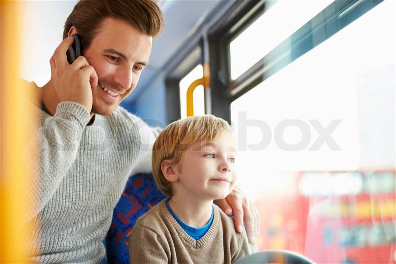 Father Using Mobile Phone On Bus Journey With Son, stock photo