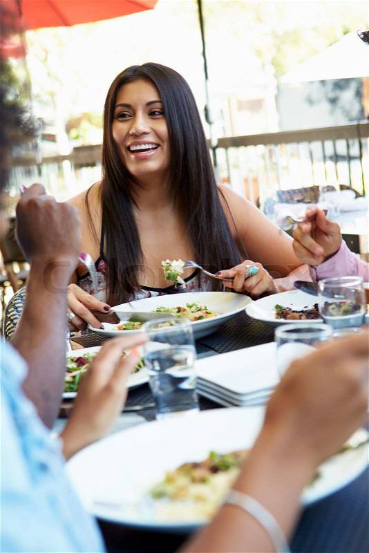 Woman Enjoying Meal At Outdoor Restaurant With Friends, stock photo