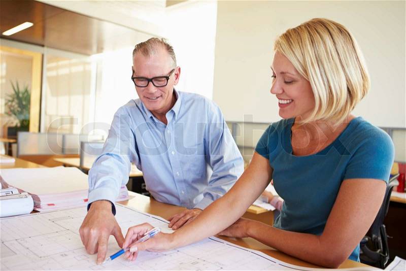 Architects Studying Plans In Modern Office Together, stock photo