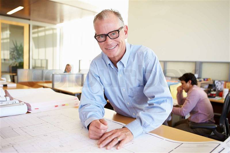 Male Architect Studying Plans In Office, stock photo
