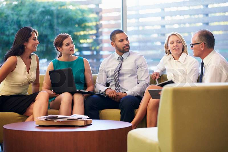 Group Of Businesspeople Having Meeting In Office Lobby, stock photo