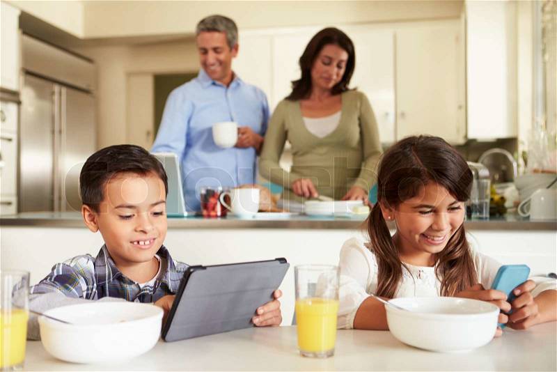 Hispanic Family Eating Breakfast Using Digital Devices, stock photo