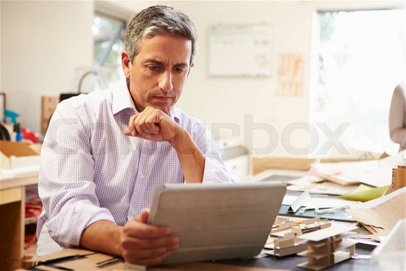 Architect Making Model In Office Using Digital Tablet, stock photo