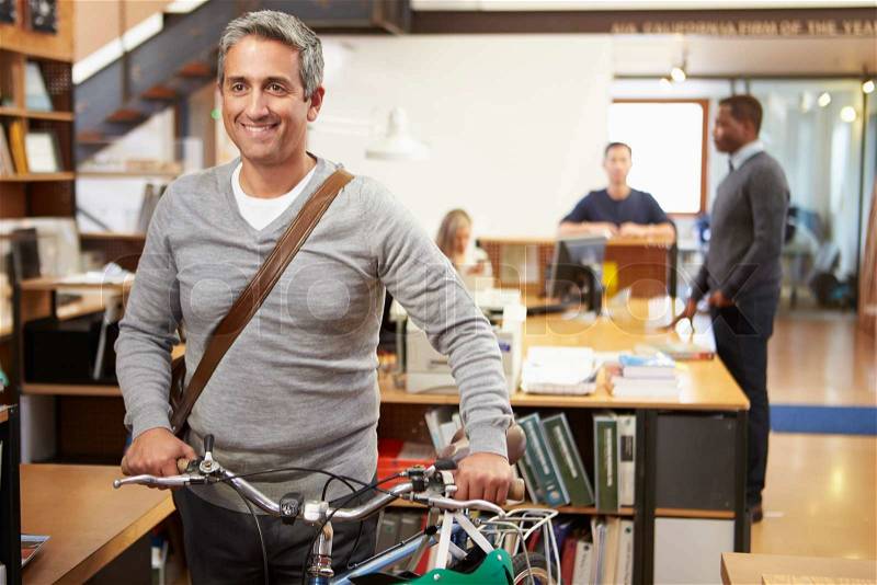 Architect Arrives At Work On Bike Pushing It Through Office, stock photo