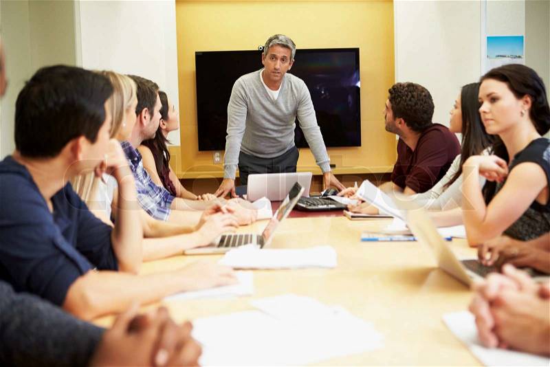 Male Boss Addressing Meeting Around Boardroom Table, stock photo