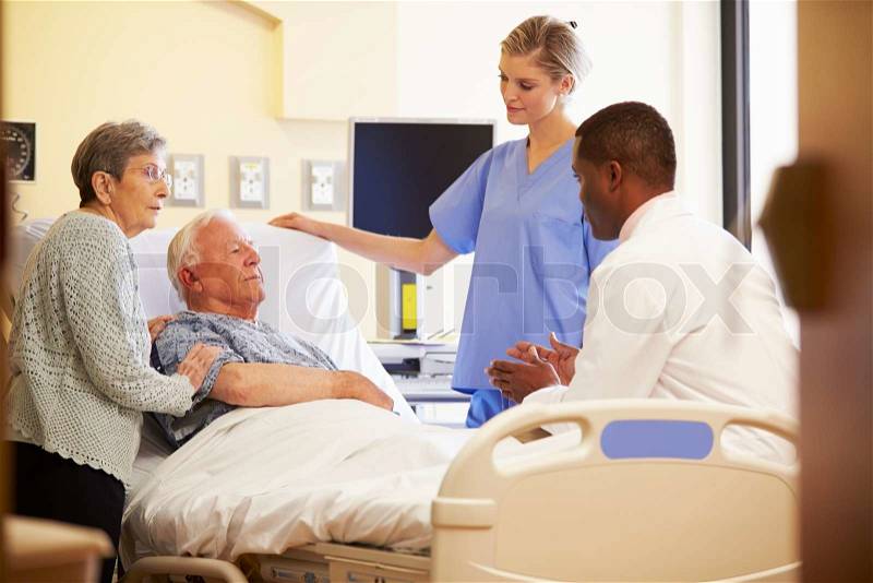 Medical Team Meeting With Senior Couple In Hospital Room, stock photo