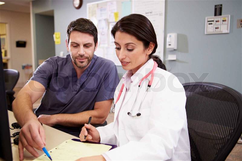 Female Doctor With Male Nurse Working At Nurses Station, stock photo