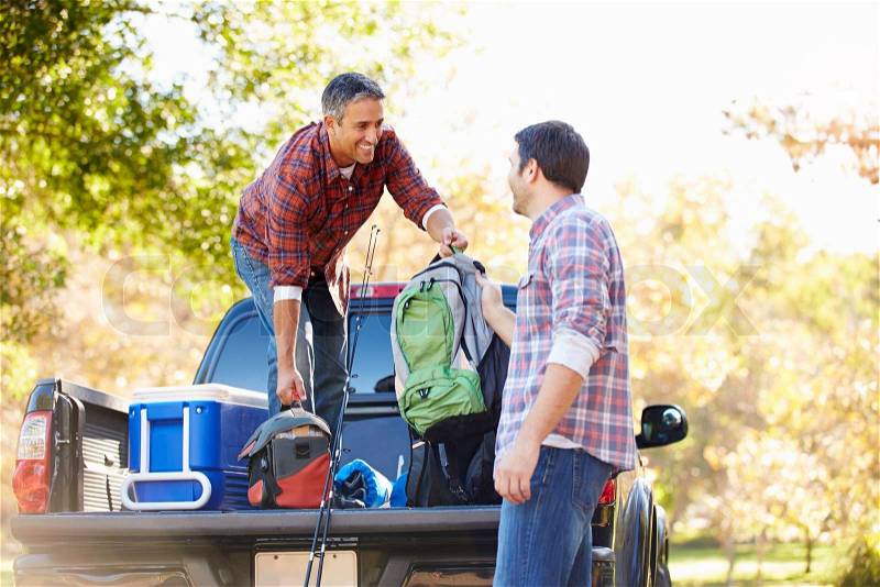 Two Men Unpacking Pick Up Truck On Camping Holiday, stock photo
