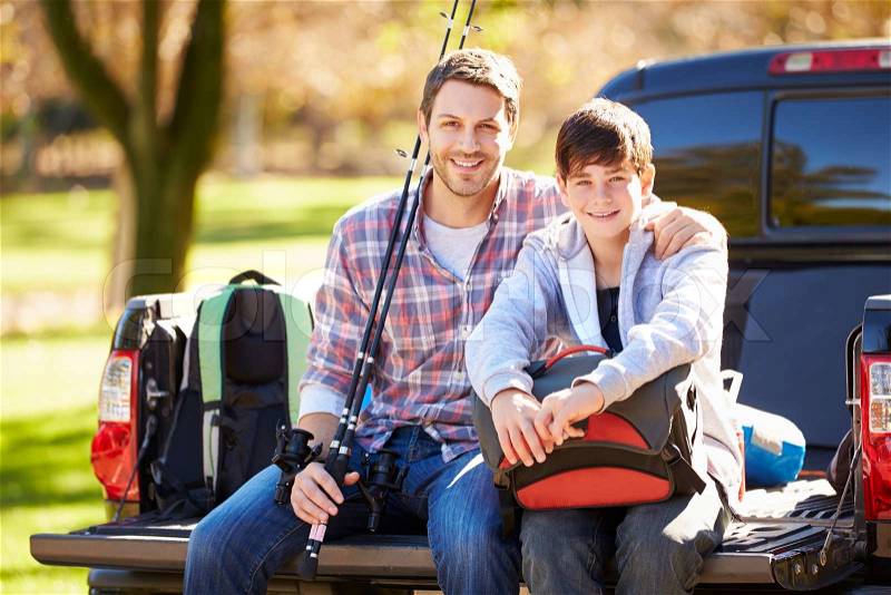 Father And Son Sitting In Pick Up Truck On Camping Holiday, stock photo