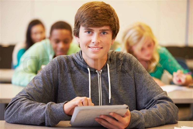 Male High School Student Studying At Desk In Classroom, stock photo