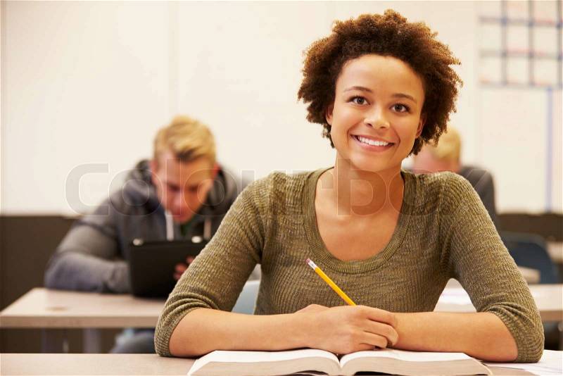 Female High School Student Studying At Desk In Classroom, stock photo