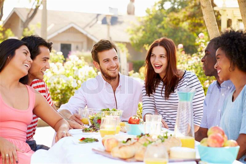 Group Of Friends Enjoying Meal At Outdoor Party In Back Yard, stock photo