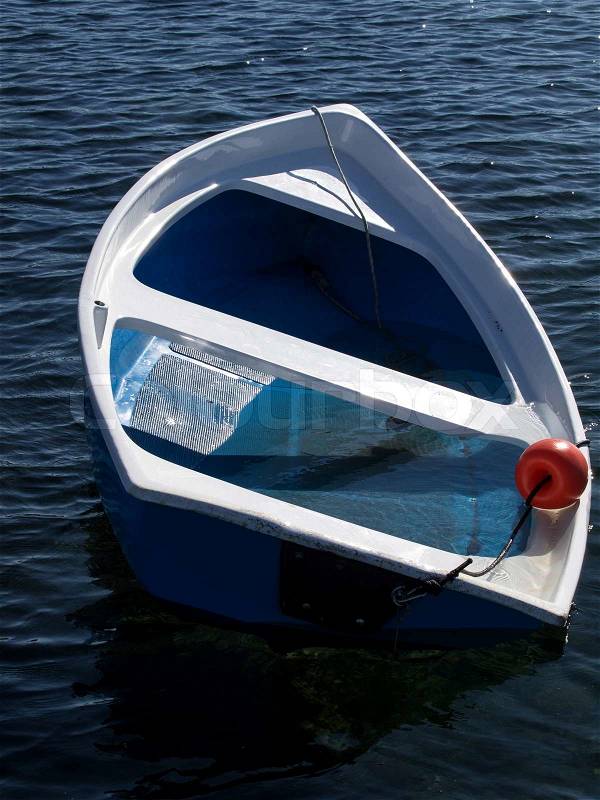 Small blue plastic boat sinking after storm, stock photo