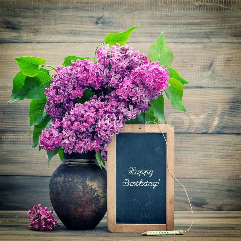 Bouquet of lilac flowers on wooden background. blackboard with sample text Happy Birthday! retro style toned picture, stock photo