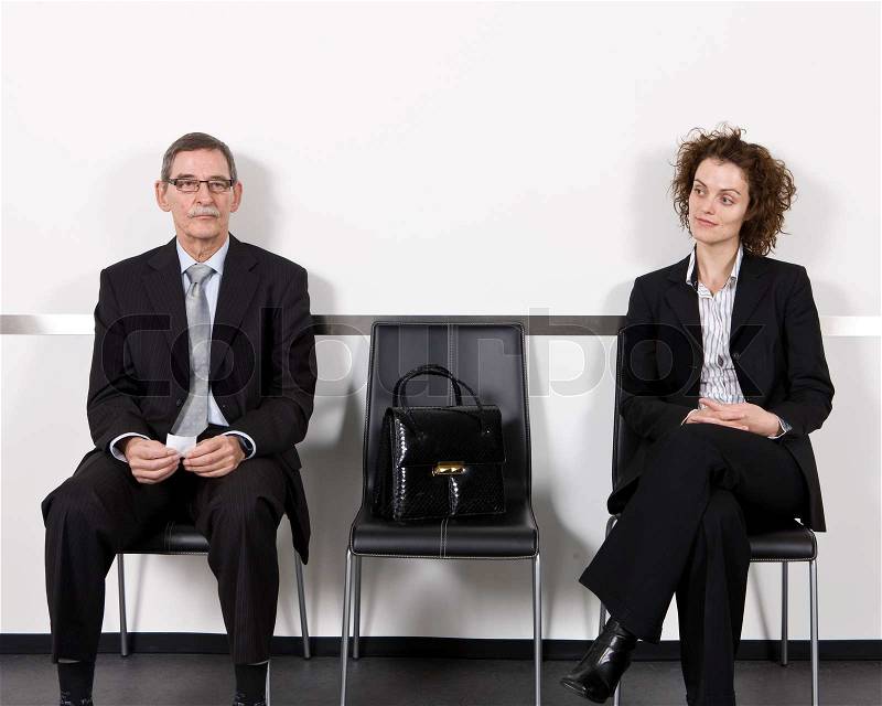 An elderly businessman and a businesswoman in a waiting room, stock photo