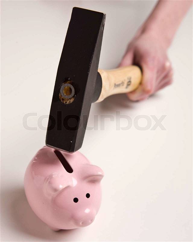A hand ready to break a piggy bank, stock photo