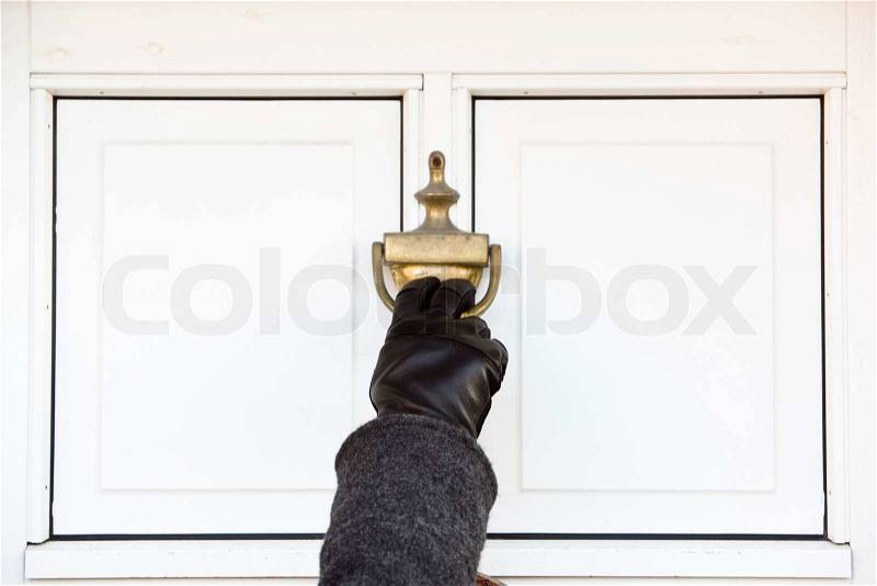A hand knocking on the door, stock photo