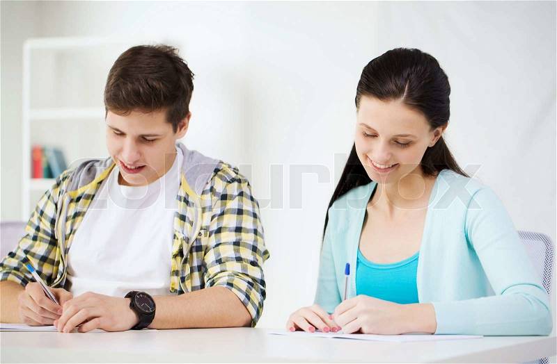 Education and school concept - two smiling students with textbooks at school, stock photo