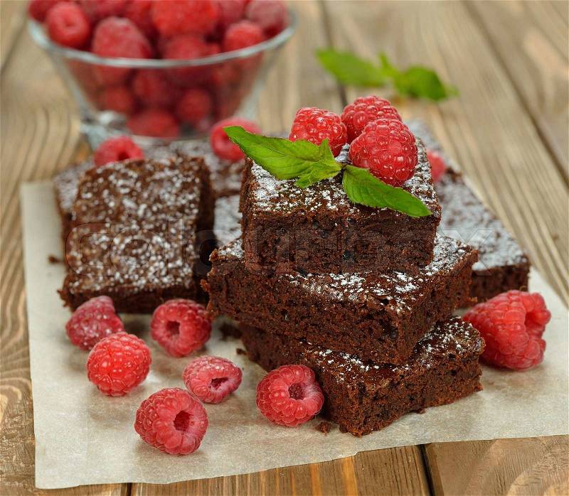 Chocolate brownies with raspberries on brown background, stock photo