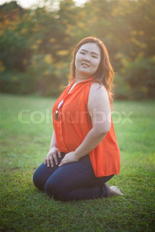 Happy fatty asian woman posing outdoor in a park, stock photo