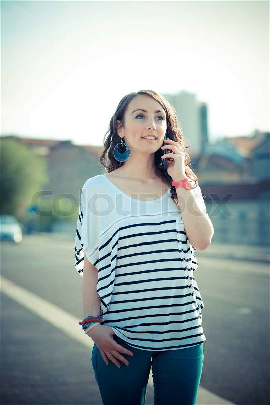 Young beautiful brunette woman with smart phone in the city, stock photo
