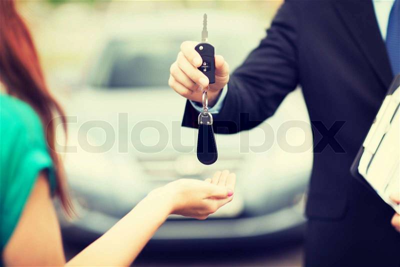Transportation and ownership concept - customer and salesman with car key outside, stock photo
