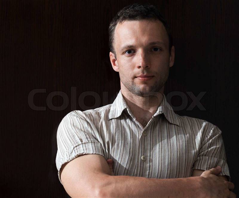 Portrait of young strong man above black background, stock photo