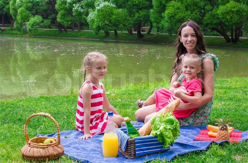 Cute little girl and happy mom picnicking in the park outdoor, stock photo