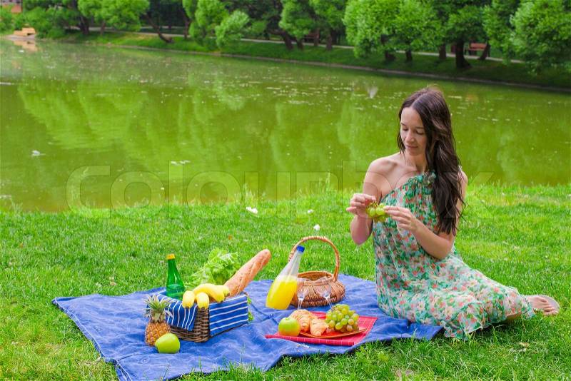 Young happy woman picnicking and relaxing outdoors, stock photo
