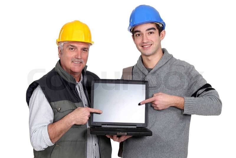 Builder and youth worker pointing at laptop, stock photo