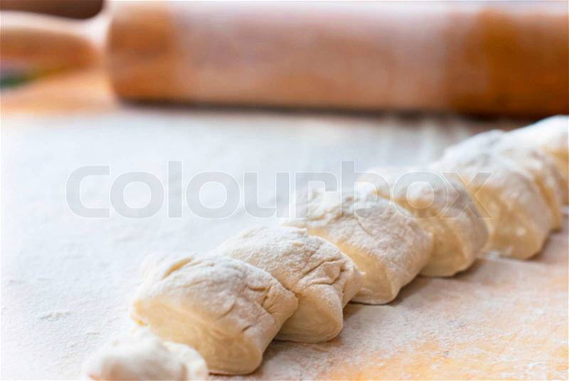 Small pieces of dough with flour on a wooden board with a rolling pin, stock photo