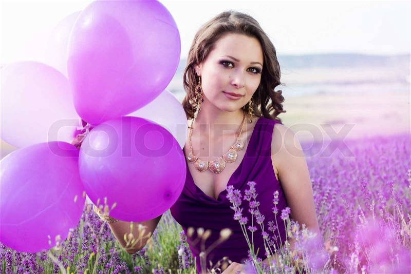 Adorable girl with purple balloons in lavender field. Summer freedom enjoy concept, stock photo