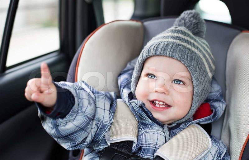 Happy toddler boy sitting in the car seat , stock photo