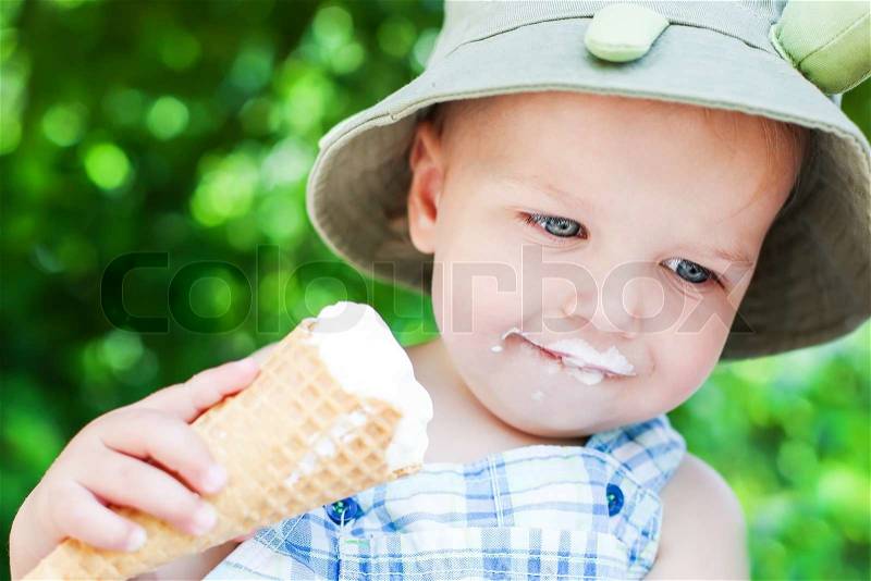 Happy toddler boy eating ice cream on a summer day, stock photo