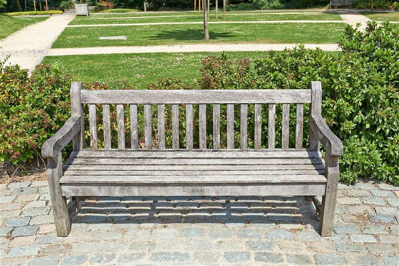 Wooden park bench in the garden in cool perspective, stock photo