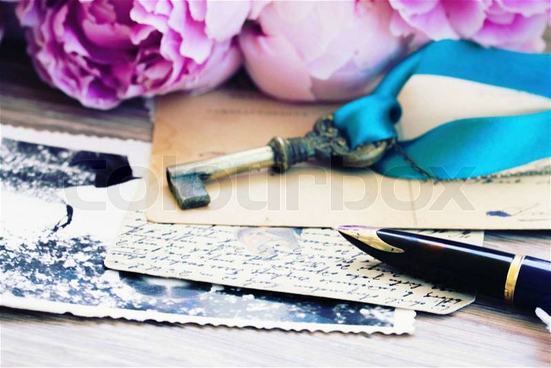 Old golden quill pen and antique letters with peonies flowers, shallow focus on pen feather, stock photo